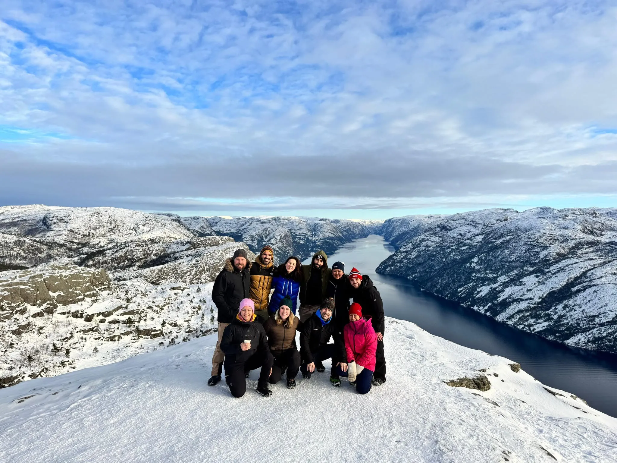 Groep op een besneeuwde bergtop boven een fjord
