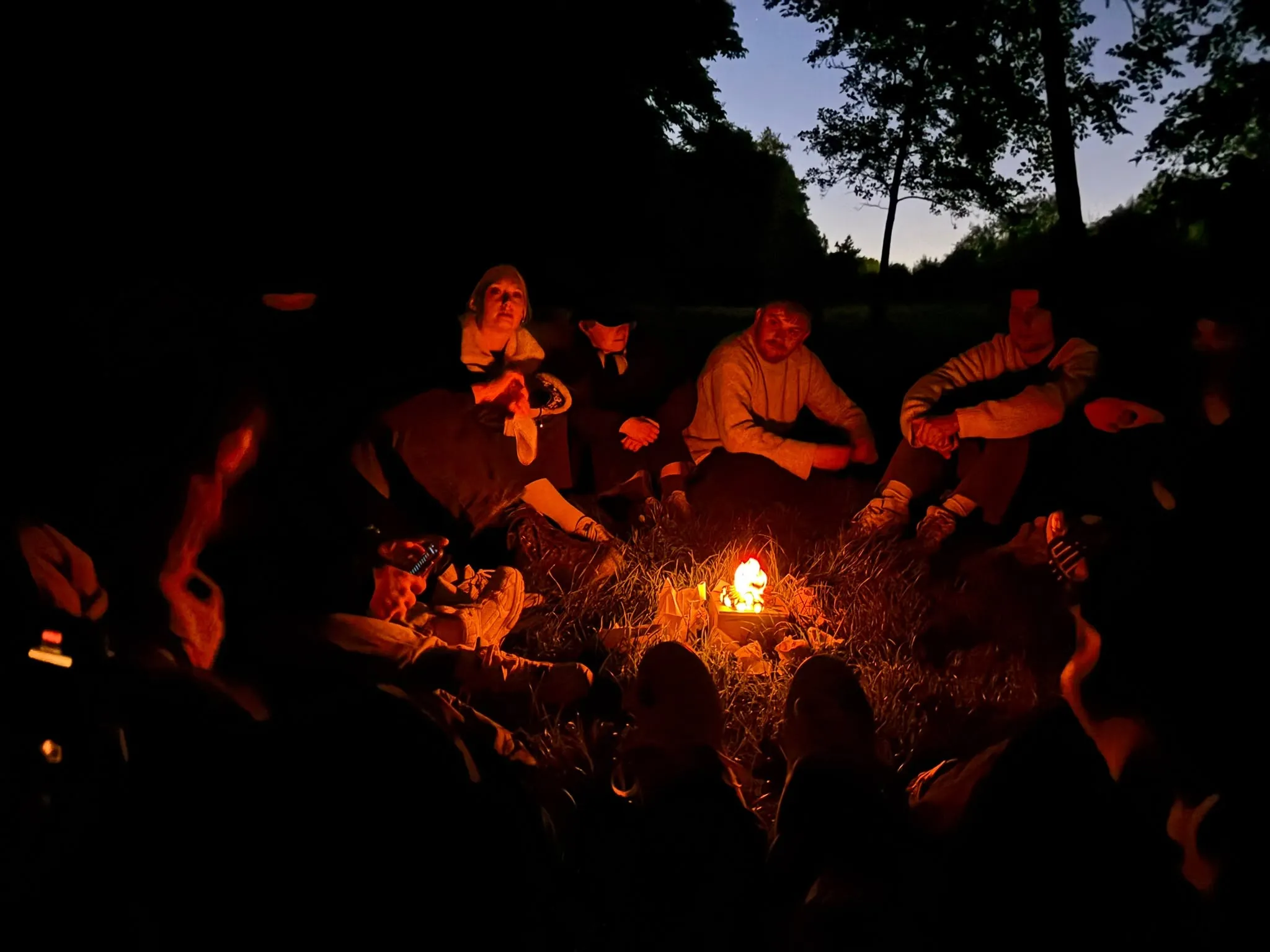 Deelnemers rond een kampvuur in de avond